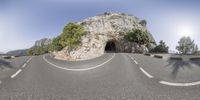 a fisheye lens photo of the road and tunnel near the trees on the side of a mountain