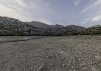 the dirt area of a rocky field in the middle of nowhere, with mountains on either side