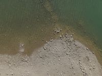 a view of the shoreline, from above with lots of rocks and pebbles strewn in the water