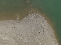 a view of the shoreline, from above with lots of rocks and pebbles strewn in the water