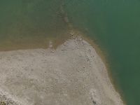 a view of the shoreline, from above with lots of rocks and pebbles strewn in the water