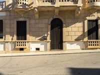 a person walks past an old building with ornate architecture on a sunny day with lots of sunlight