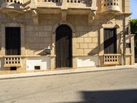 a person walks past an old building with ornate architecture on a sunny day with lots of sunlight