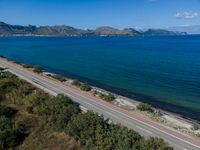 a highway that is going over some water and hills in the distance are trees and the ocean