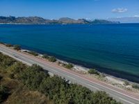 a highway that is going over some water and hills in the distance are trees and the ocean