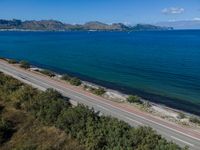 a highway that is going over some water and hills in the distance are trees and the ocean