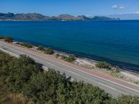 a highway that is going over some water and hills in the distance are trees and the ocean