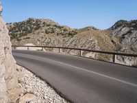 a road near the side of a mountain side road that has an overhang on both sides and a curved road over a cliff