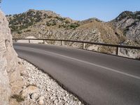 a road near the side of a mountain side road that has an overhang on both sides and a curved road over a cliff