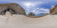 a panoramic view of a curved walkway on the coast side with large cliff formations in the background