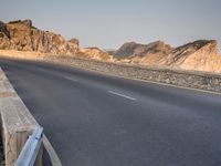 a car drives along the empty road in front of the ocean and rocky mountains at the edge