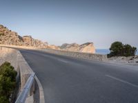 a car drives along the empty road in front of the ocean and rocky mountains at the edge