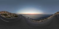 there is a large lens in the sky above the ocean and the road goes right past the beach