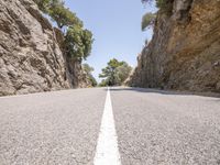 a white line in the middle of a mountain road that runs between a rocky cliff side