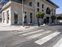 the empty street in front of a white building with an odd entrance to it is almost crosswalking