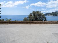 the view of the ocean from a stone bench at a seaside clifftop location under a cloudy blue sky