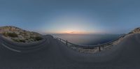 a fish eye view of a curved road overlooking the ocean during sunset in europe as seen on this 360 - degree photograph