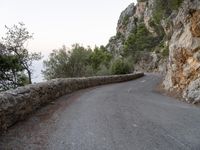 the road is curved and winding around rocks and trees on both sides of the street