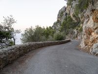 the road is curved and winding around rocks and trees on both sides of the street