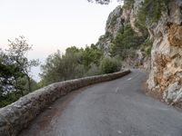 the road is curved and winding around rocks and trees on both sides of the street