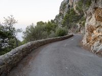 the road is curved and winding around rocks and trees on both sides of the street