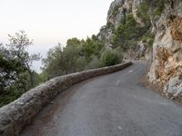 the road is curved and winding around rocks and trees on both sides of the street