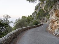 the road is curved and winding around rocks and trees on both sides of the street