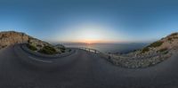 fish eye lens of a highway at sunset overlooking the ocean and mountain range at dusk