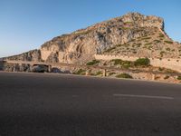 a stone cliff is in the background as a man on a skateboard passes by