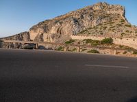 a stone cliff is in the background as a man on a skateboard passes by