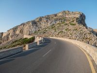 the road is curving with a long curve on one side and a steeply up hill behind