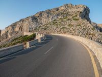 the road is curving with a long curve on one side and a steeply up hill behind