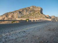 the motorcycle is parked at the edge of the stone road near a mountain and sky