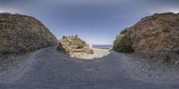 the narrow road runs between two large rocks and a grassy area with green grass on both sides