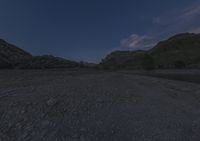 a night view of a large body of water with trees in front of a rocky mountain