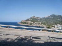 a motorcycle parked on the side of a road near a sea and mountains in the background