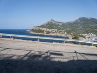 a motorcycle parked on the side of a road near a sea and mountains in the background