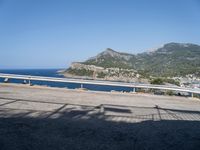 a motorcycle parked on the side of a road near a sea and mountains in the background