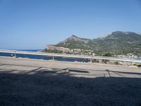 a motorcycle parked on the side of a road near a sea and mountains in the background