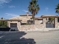 a large house with two cars parked outside it and a palm tree by the side of the road