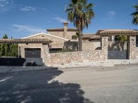 a large house with two cars parked outside it and a palm tree by the side of the road