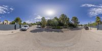 the reflection of two vans driving on an empty road in a desert area under a sun