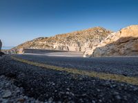 a motorcycle on a mountain road with mountains behind it and no clouds in the sky