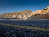 a motorcycle on a mountain road with mountains behind it and no clouds in the sky