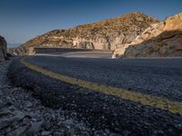 a motorcycle on a mountain road with mountains behind it and no clouds in the sky