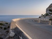 a scenic road stretches into the ocean from the beach with an arched wall surrounding it