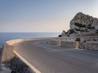 a scenic road stretches into the ocean from the beach with an arched wall surrounding it