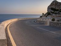 a scenic road stretches into the ocean from the beach with an arched wall surrounding it