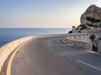 a scenic road stretches into the ocean from the beach with an arched wall surrounding it