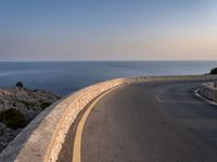 a scenic road stretches into the ocean from the beach with an arched wall surrounding it